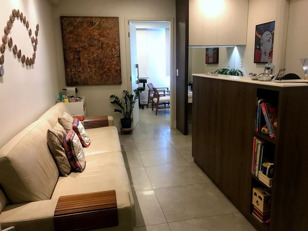 Recepção da clínica, com sofá, quadros e livros infantis