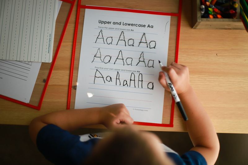 Criança traçando as letras do alfabeto em uma folha de exercícios