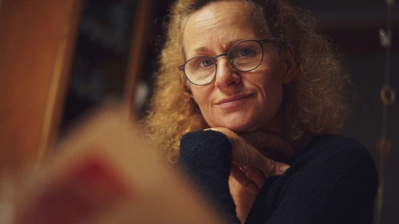 Mulher de óculos, com um livro em primeiro plano