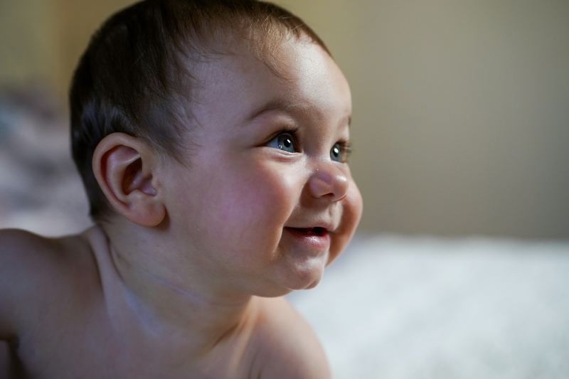 Bebê sorrindo e acompanhando algo com o olhar