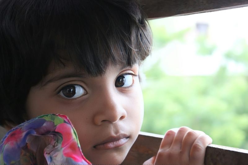 Criança pequena de olhos castanhos olhando com atenção